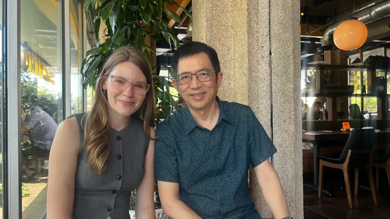 Two colleagues sitting together and smiling at a restaurant table.