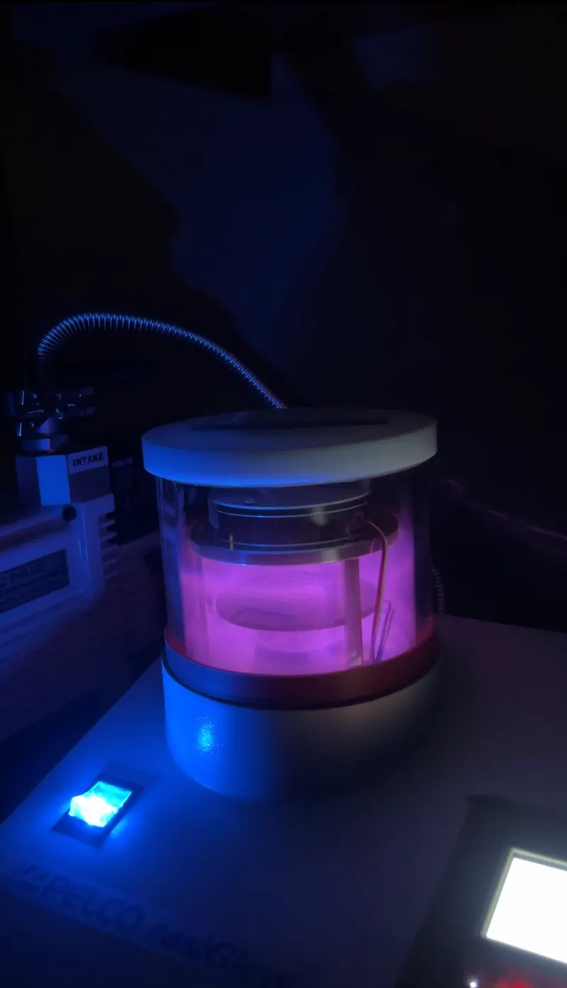 Glowing plasma charging a TEM grid in the dark.